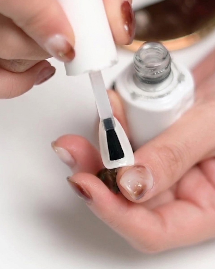 Una mano posicionada dentro de una lámpara de uñas UV/LED con luz brillando, indicando el proceso de curado.