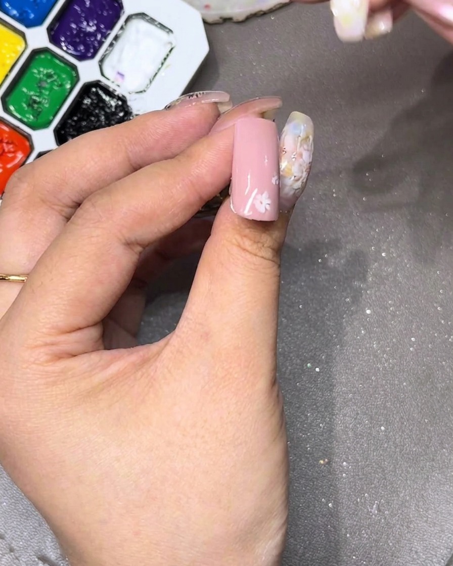 Primer plano de una uña mostrando el pétalo blanco inicial dibujado en la parte superior.
