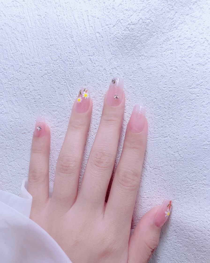 Un pincel aplicando esmalte de gel rosa nude sobre una uña natural.