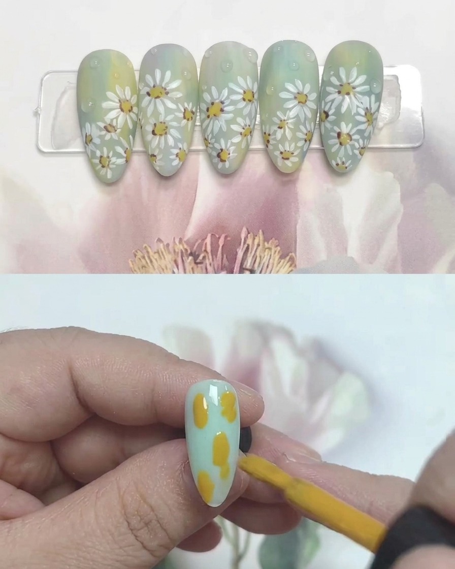 Un pincel de uñas aplicando pequeñas gotas de gel amarillo, azul y blanco sobre una uña.