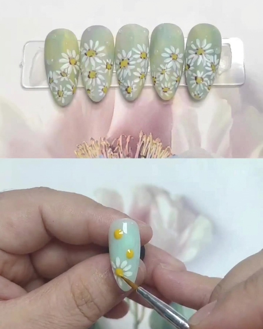 Un pincel aplicando una capa de top coat mate sobre el diseño de uñas de margaritas terminado.