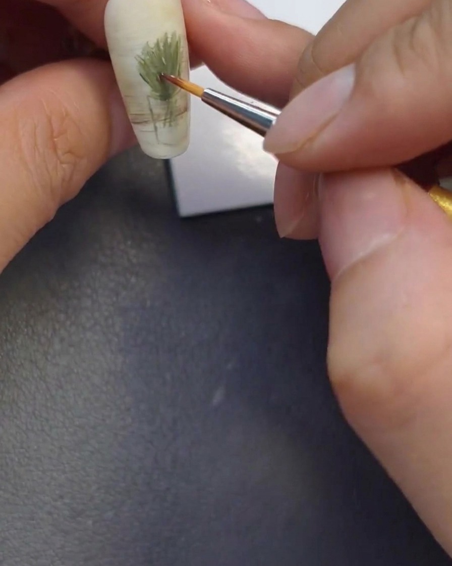 Primer plano de un pincel aplicando puntos de gel marrón, naranja y amarillo.
