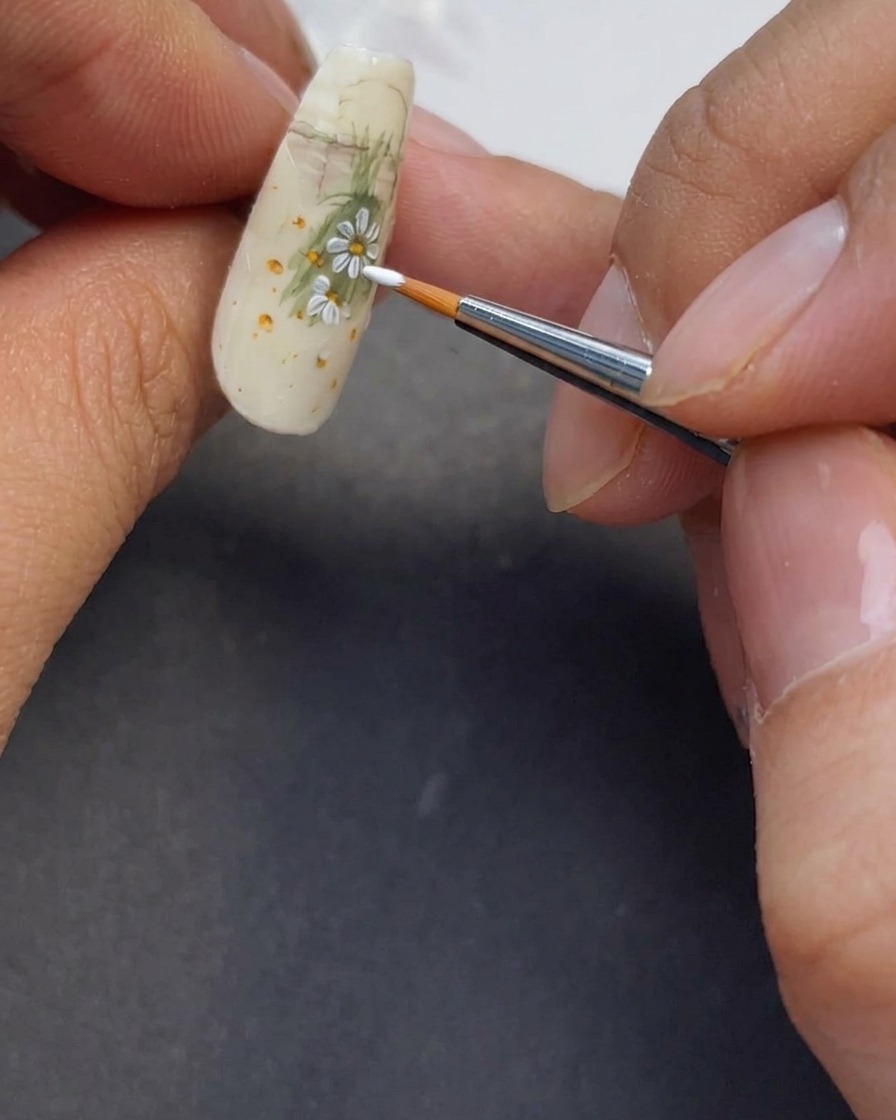 Primer plano de más pétalos blancos siendo pintados para completar el diseño.