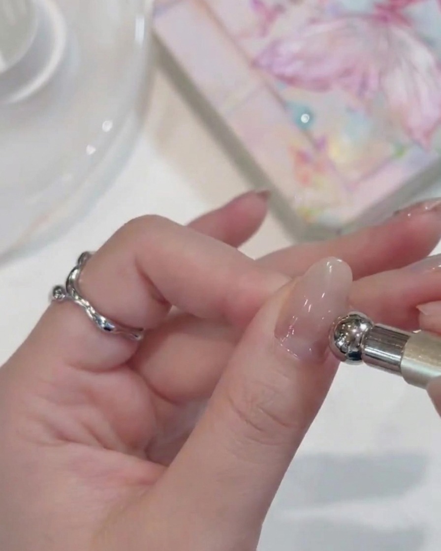 Primer plano de una mano con uñas con gel bajo una lámpara UV compacta.