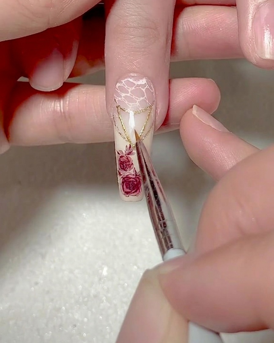 Primer plano de un pincel liner fino pintando un pequeño y preciso triángulo de gel blanco en la punta de la uña.