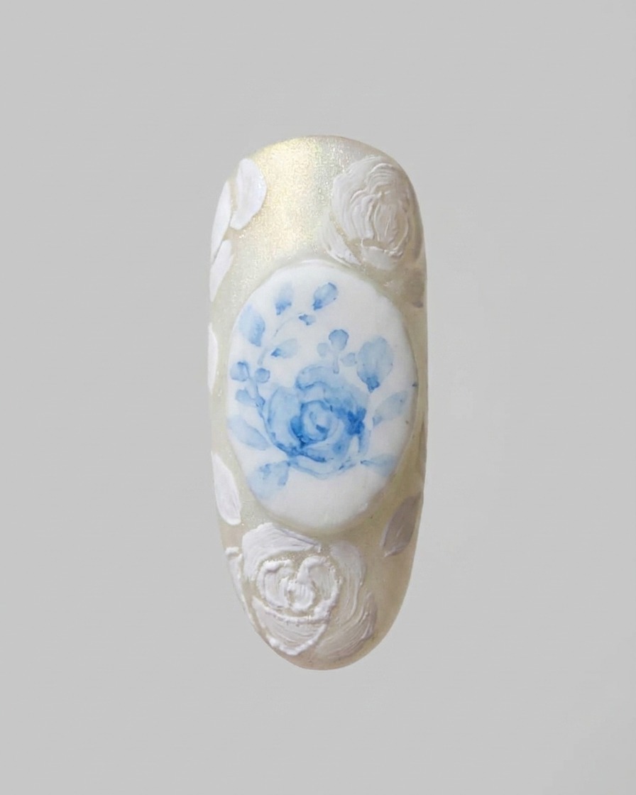 Un pincel de detalle fino añadiendo patrones de encaje blanco delgados e intrincados que conectan los diseños de rosas 3D.