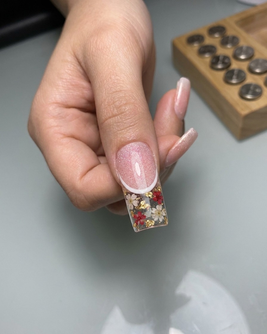 Primer plano que muestra un pincel delineador fino dibujando líneas finas de encaje blanco sobre la superficie de la uña con efecto ojo de gato curado.