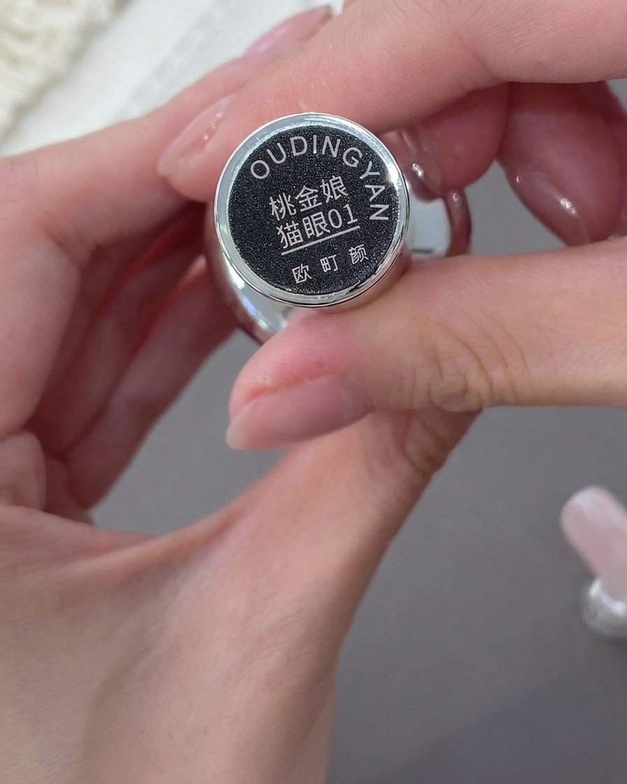 Mano sosteniendo una botella de gel cat-eye en tono rosa nude.