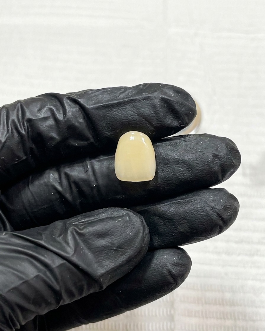 Primer plano de una uña con el diseño de líneas oscuras curado siendo colocada bajo una pequeña lámpara UV.