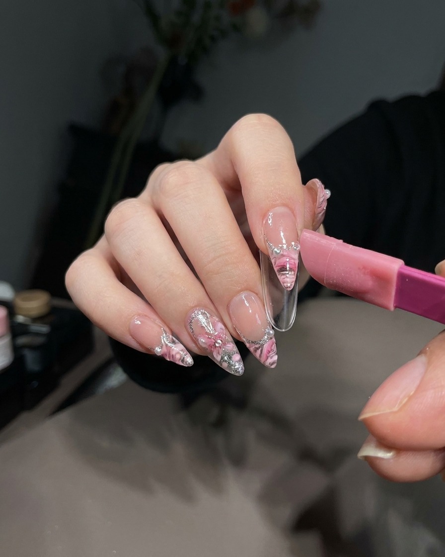Un par de pinzas levantando cuidadosamente una pegatina de manicura francesa sobre el gel blanco curado en una punta de uña.