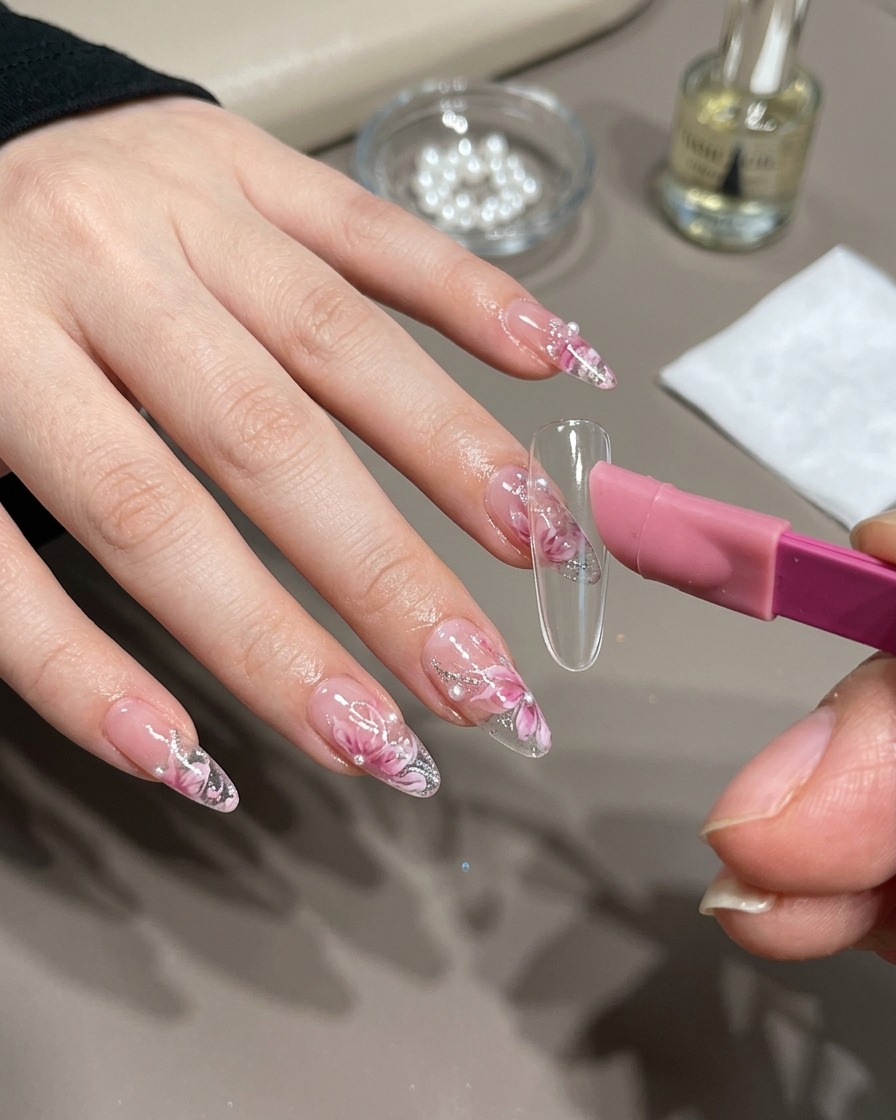 Un pincel de uñas aplicando gel magnético dorado sobre una punta de uña.