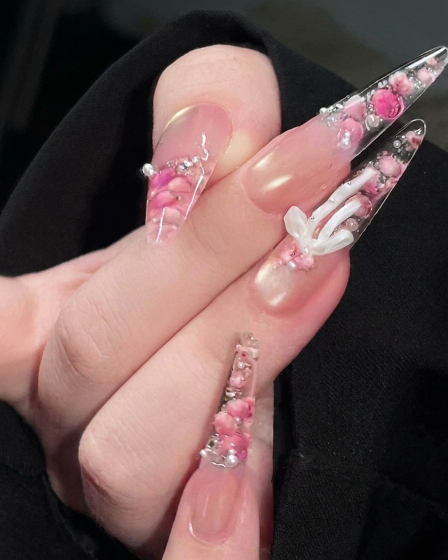 Un pincel aplicando un top coat transparente y brillante sobre la superficie del diseño de uña con rosas terminado.