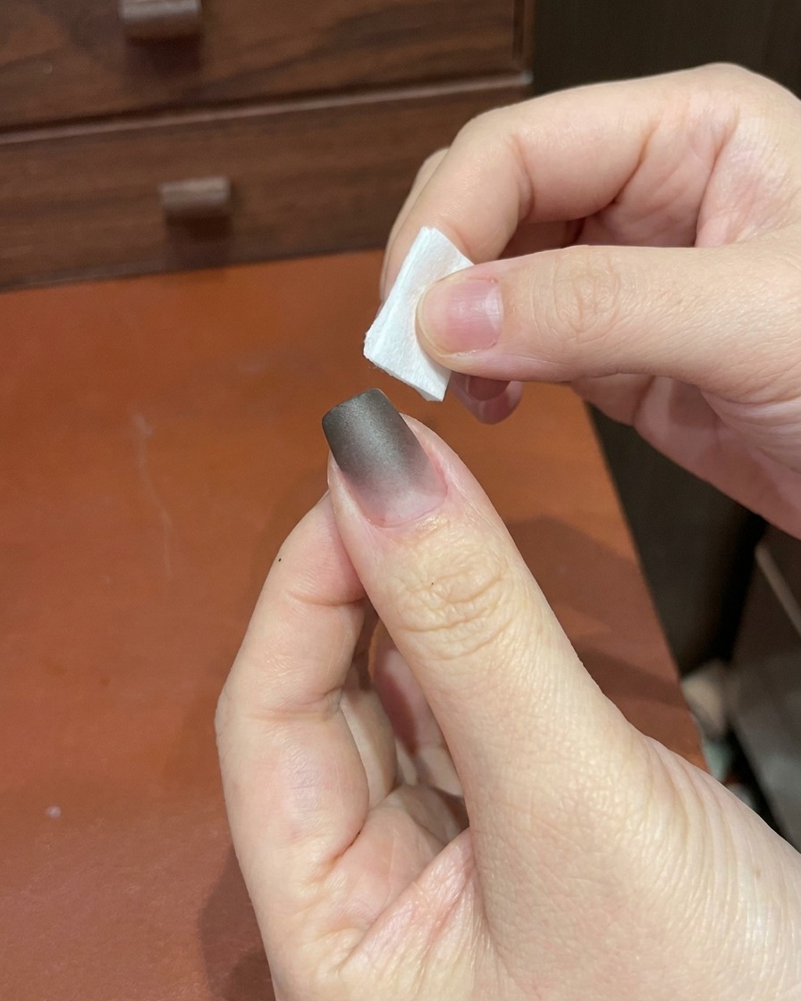 Una mano colocando un dedo bajo una lámpara de uñas UV/LED pequeña y portátil.
