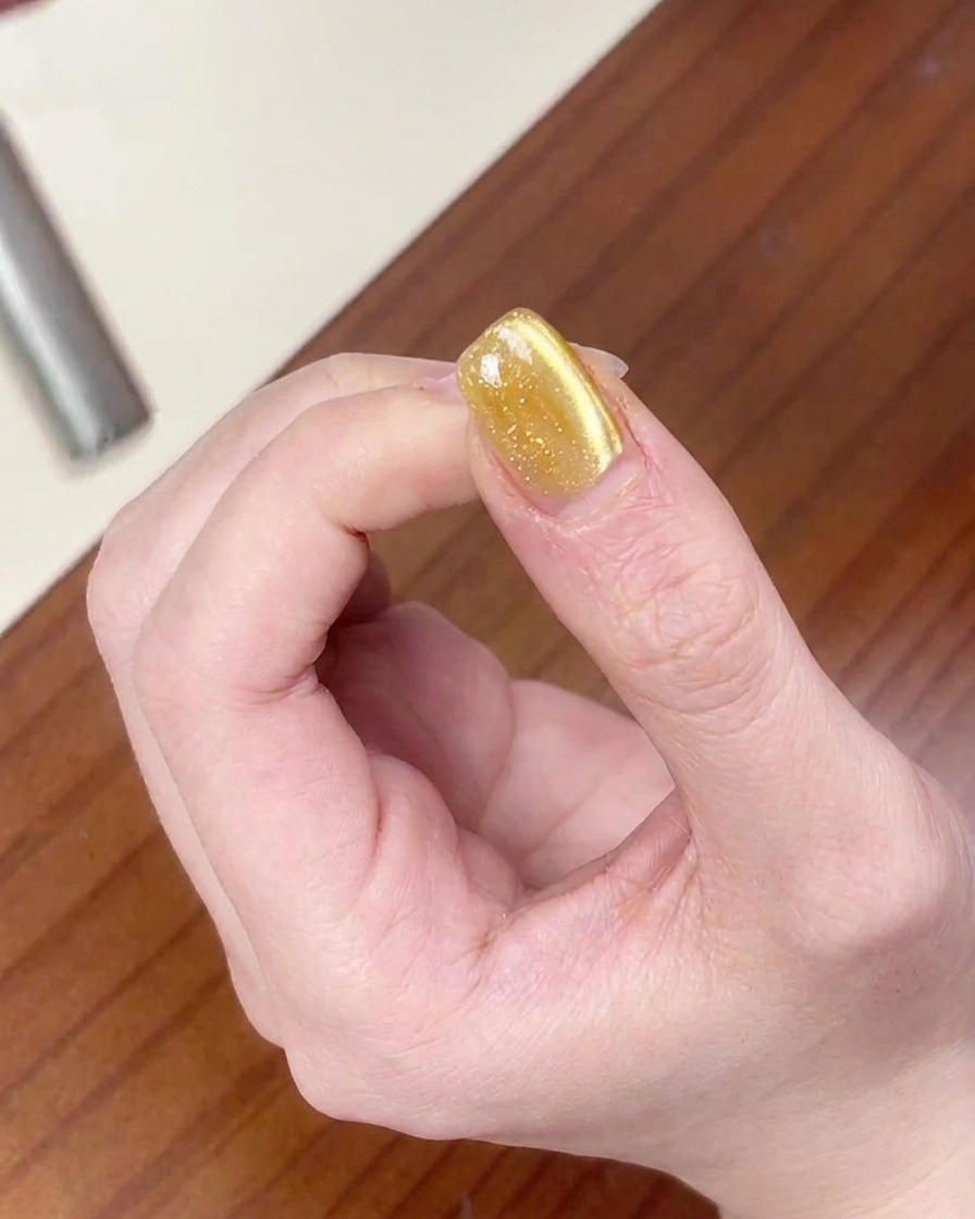 El imán arrastrando partículas magnéticas para crear un brillo de ojo de gato más ancho en la uña.