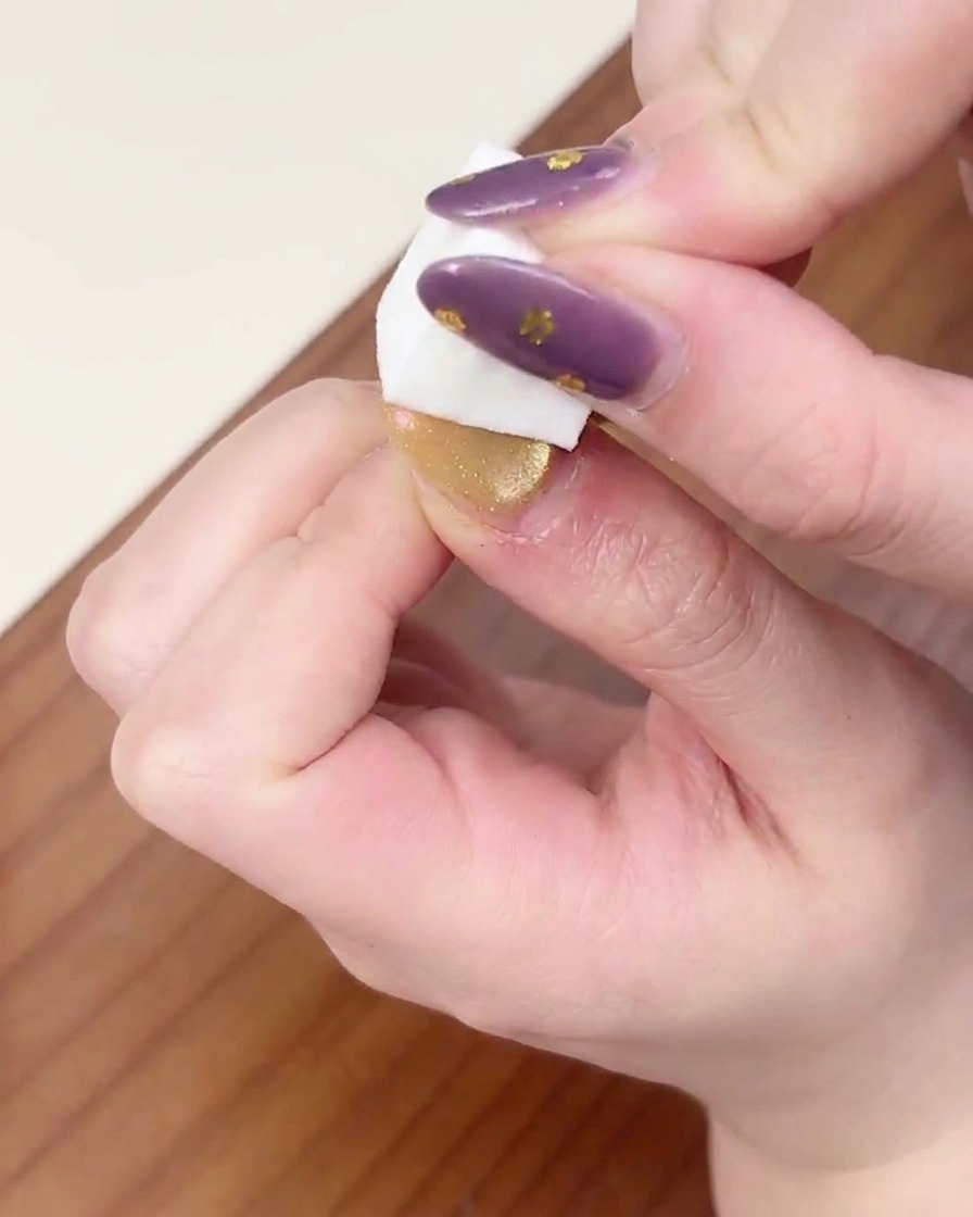 Una mano colocada bajo una lámpara profesional de uñas para curar la capa de gel degradado.