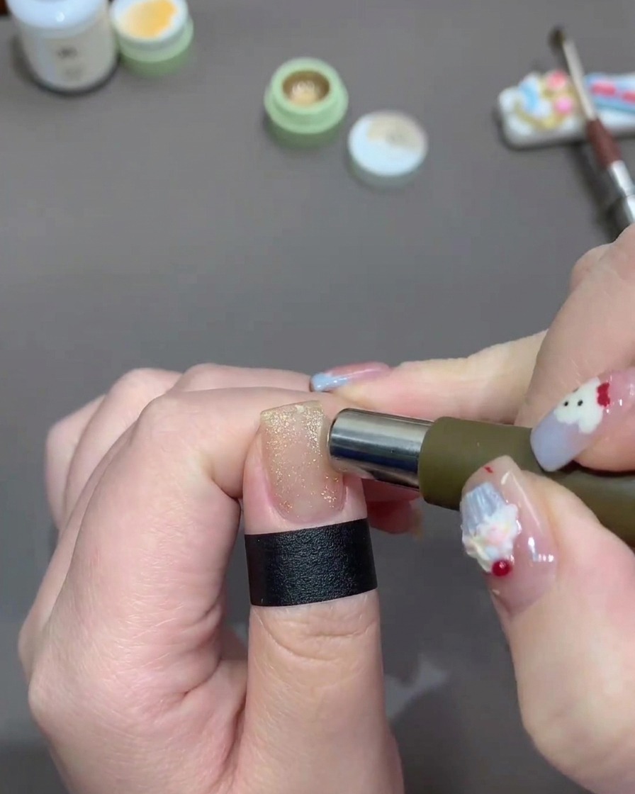 Un imán cilíndrico moviéndose alrededor de los bordes de una uña pintada con esmalte cat-eye dorado.