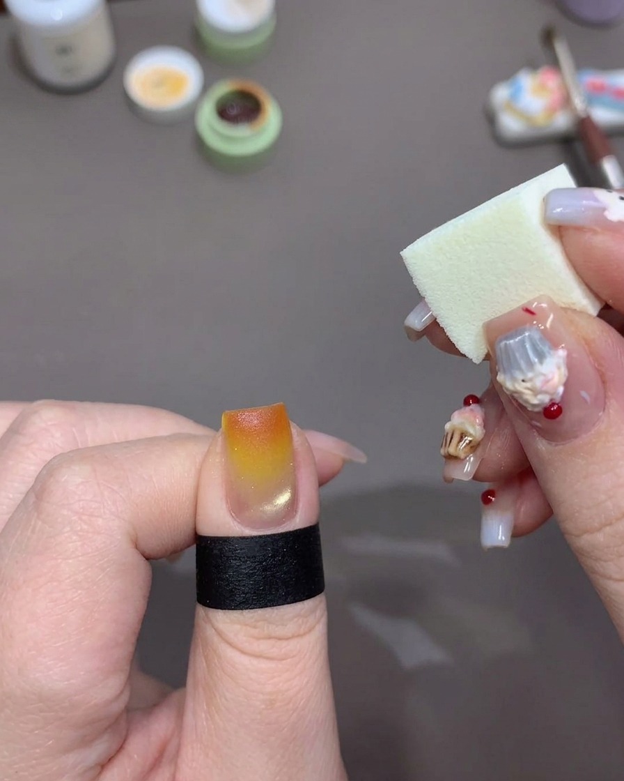 Una esponja aplicando más gel naranja en la punta de la uña para intensificar el color.