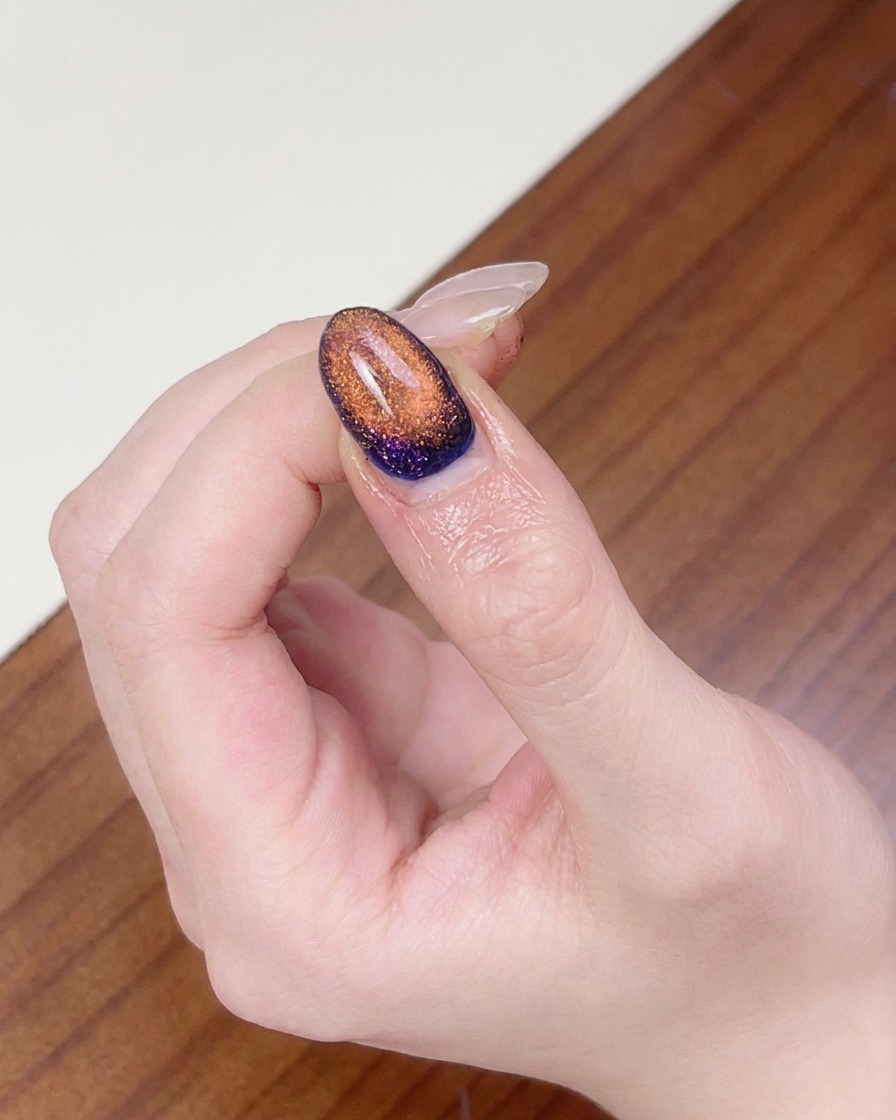 Un dedo colocado bajo una lámpara de uñas UV para curar el arte de uñas cat eye magnético completado.