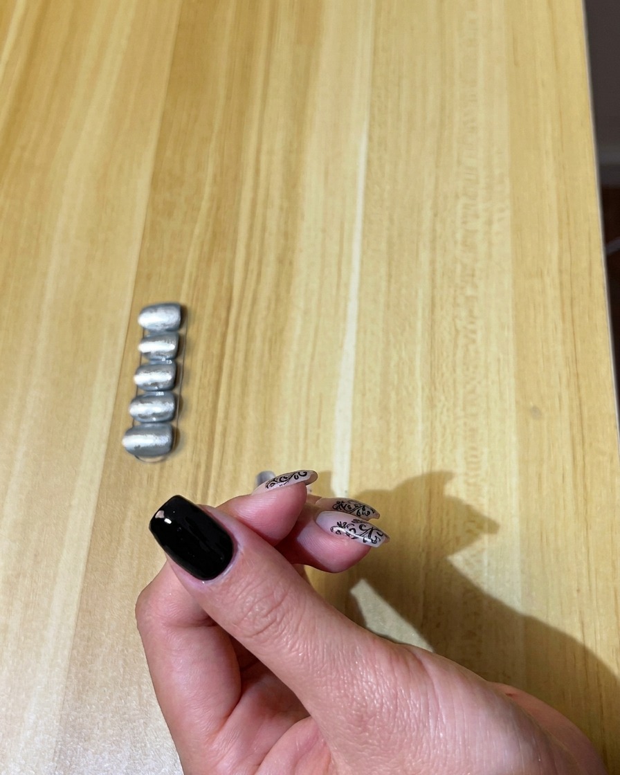 Un pincel aplicando una capa suave de esmalte de gel negro sobre una uña natural.