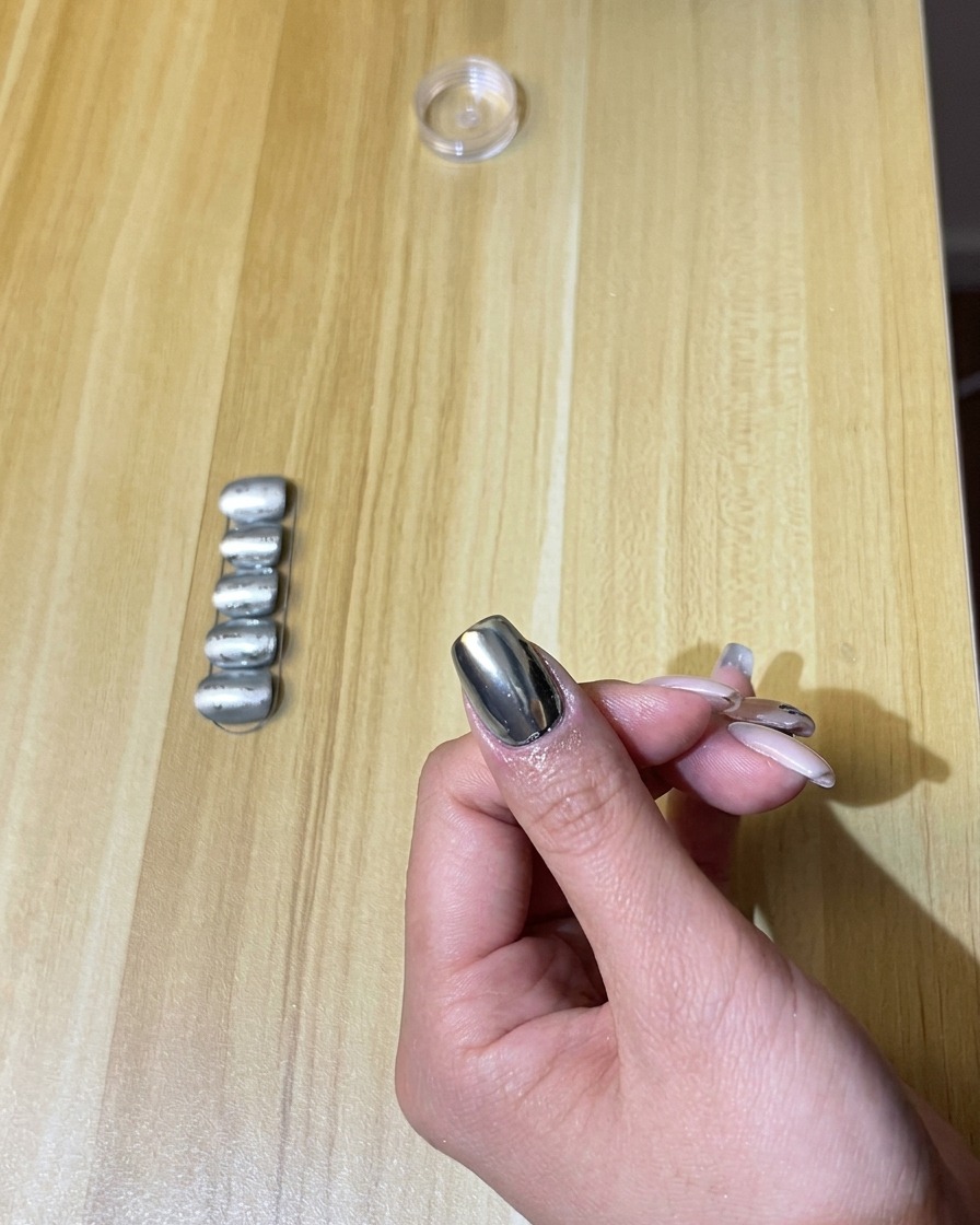 Una mano con uñas cromadas dentro de una lámpara de uñas UV/LED encendida.