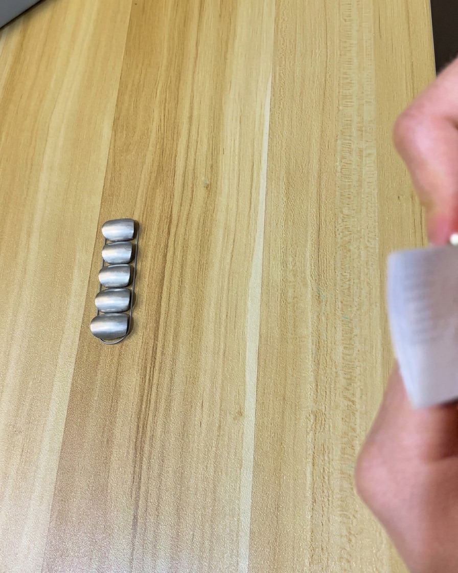 Una toallita sin pelusa siendo usada para limpiar la superficie de una uña con acabado mate.
