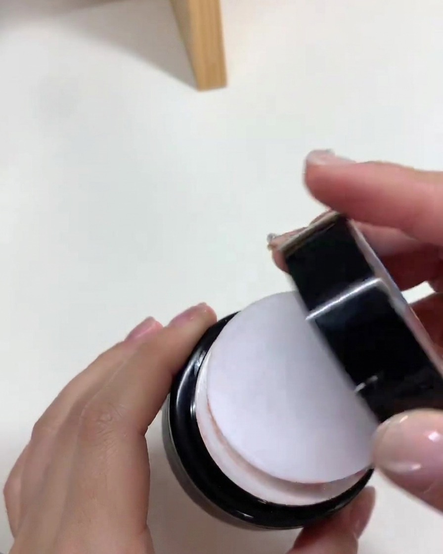 Un pincel aplicando una capa suave de esmalte de gel nude sobre una uña postiza.