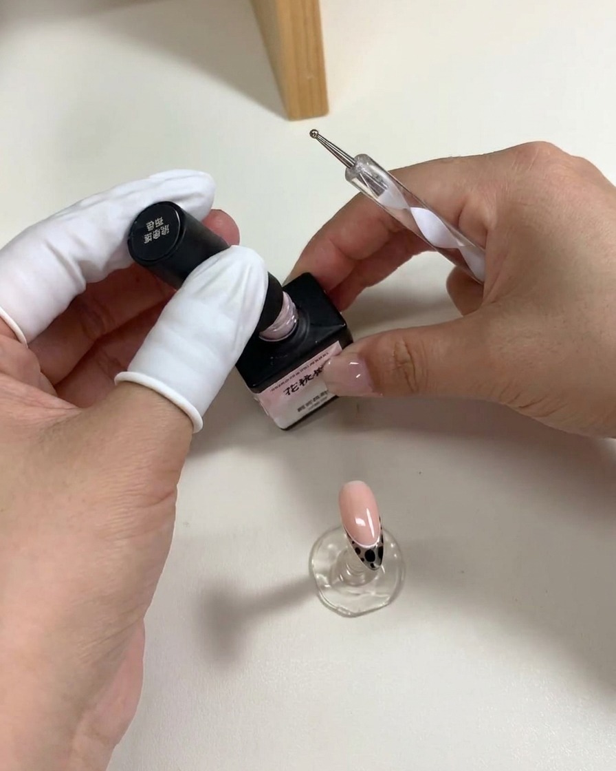 Una herramienta de puntos colocando cinco puntos de gel rosa para crear una forma de flor.