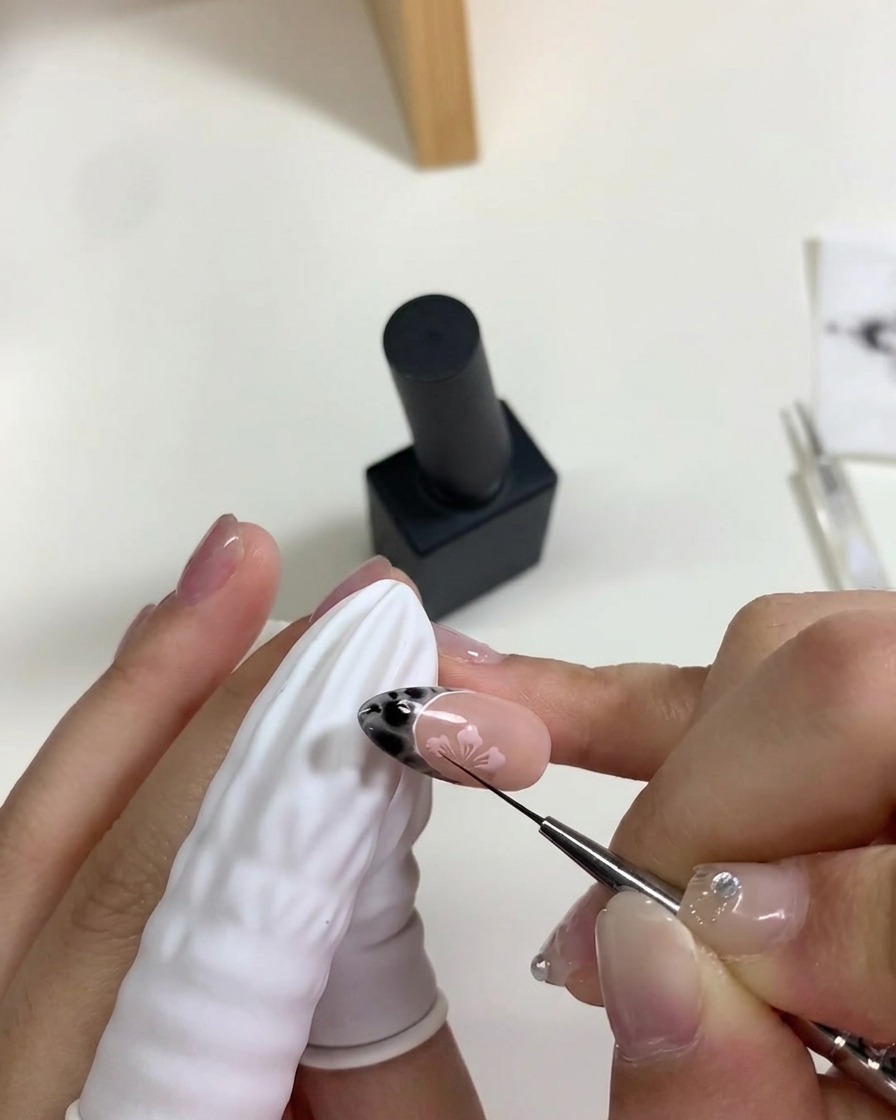 Una mano colocando una uña bajo una lámpara UV/LED mini para curar el arte de flores de cerezo.