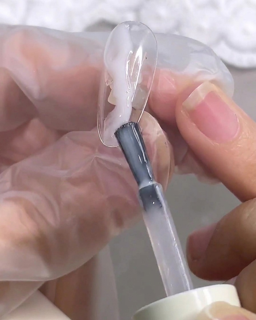 Primer plano de un pincel suavizando el blooming gel sobre la superficie de la uña.