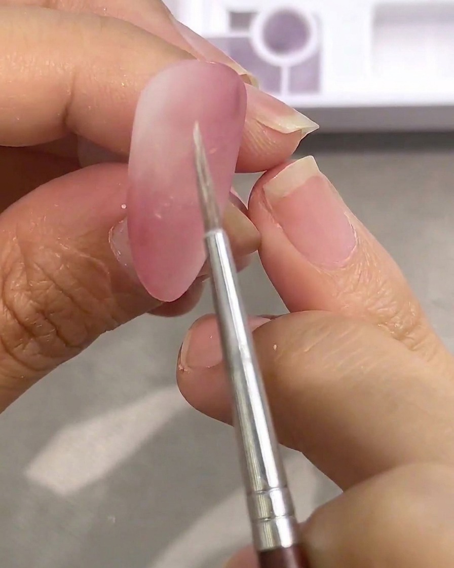 Un pincel fino sumergido en pintura acuarela blanca sobre una paleta.