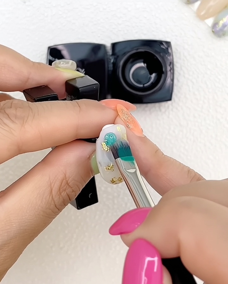 Primer plano de una mano con uñas pintadas de gel multicolor puestas bajo una lámpara UV profesional.