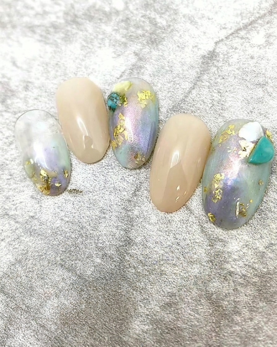 Pequeñas piezas de escamas de concha blanca aplicadas a un diseño de uñas como decoración de acento.