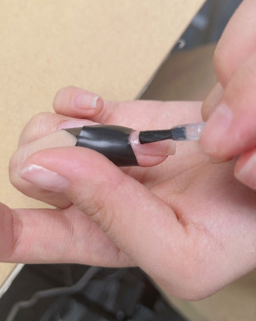 Un pincel aplicando una capa transparente y brillante de blooming gel sobre una base nude.