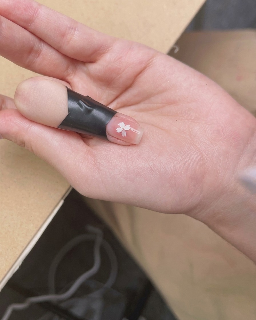Una mano colocada bajo una lámpara de uñas UV/LED compacta, enfocada en las uñas que reciben la luz.