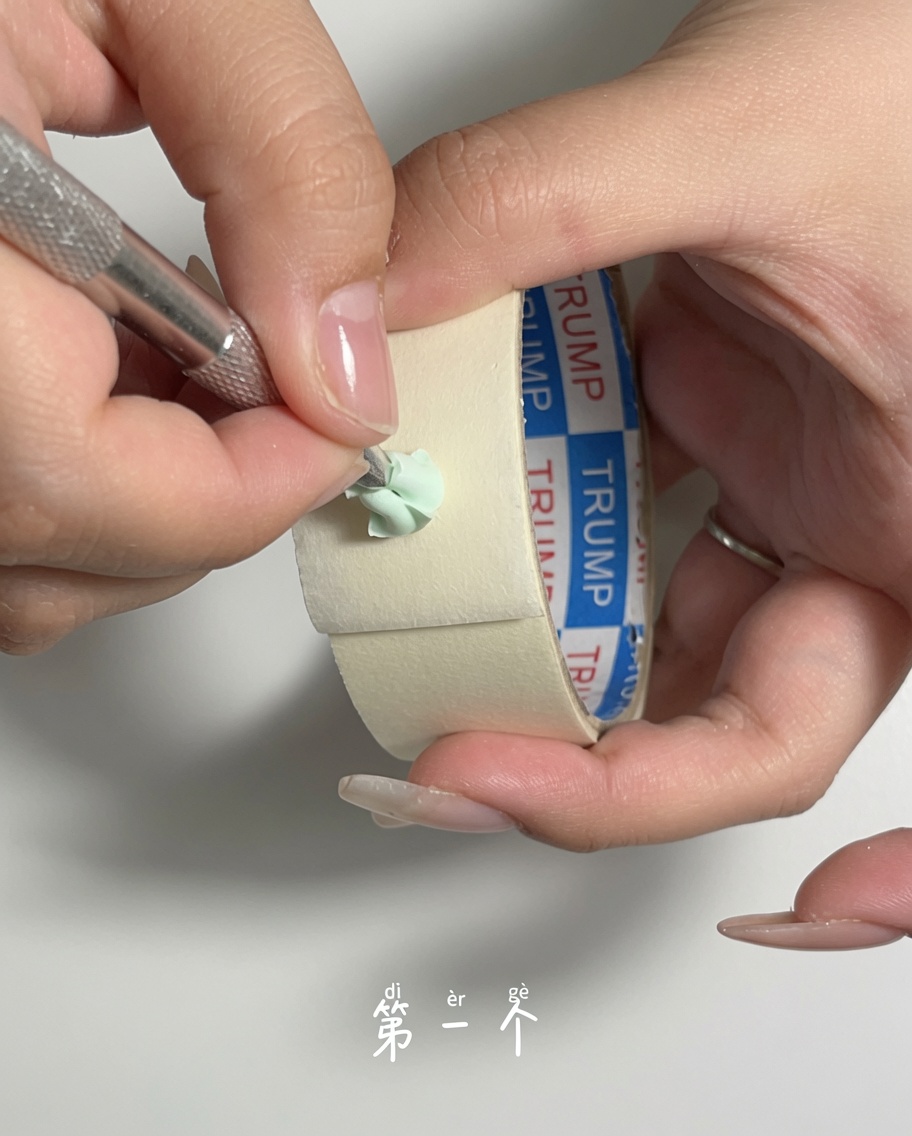 Un empujador de cutículas de metal siendo utilizado para raspar suavemente el polvo de la superficie de una esponja de maquillaje verde.