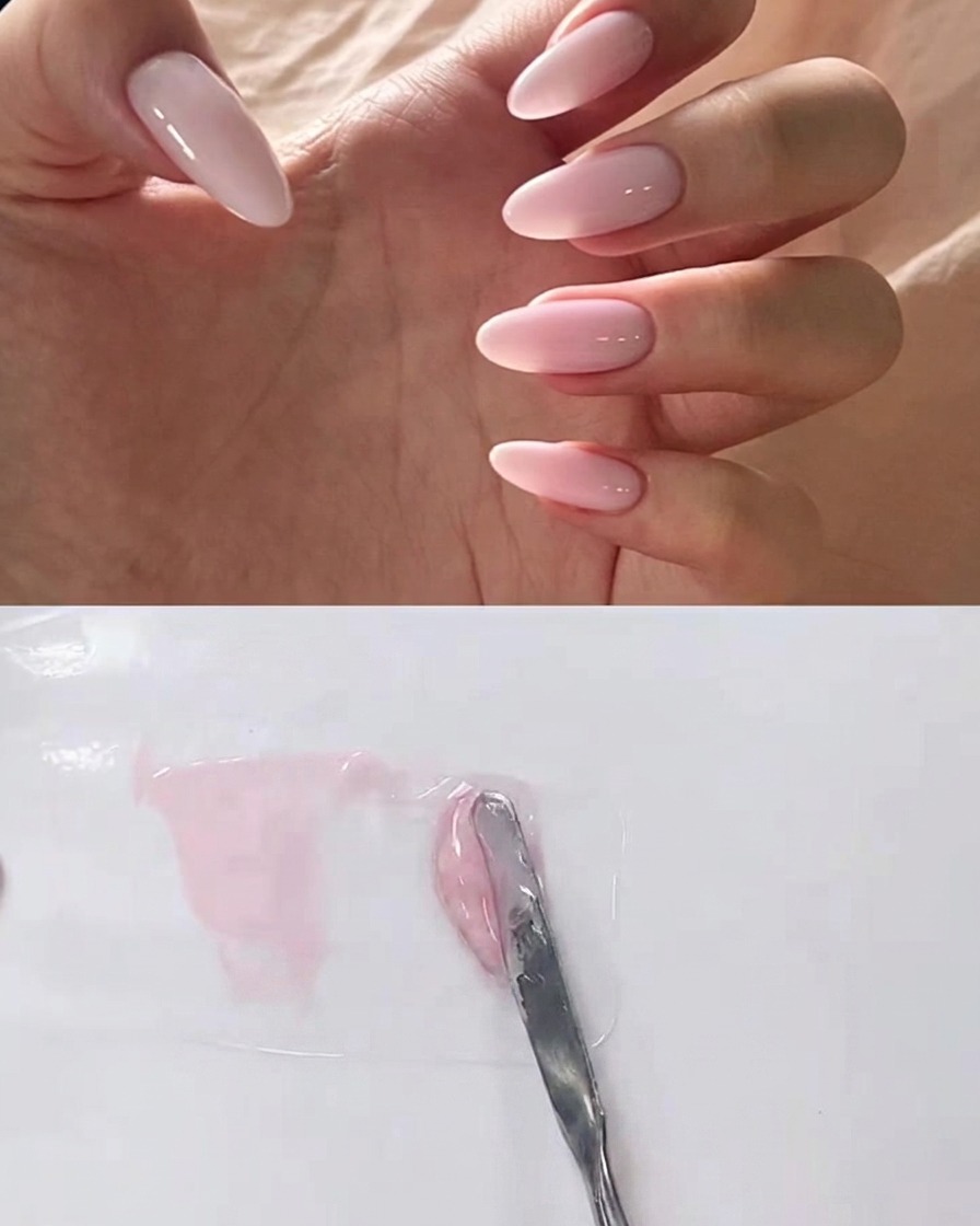 Una espátula de metal mezclando gel transparente en una mezcla de gel rosa sobre una paleta.