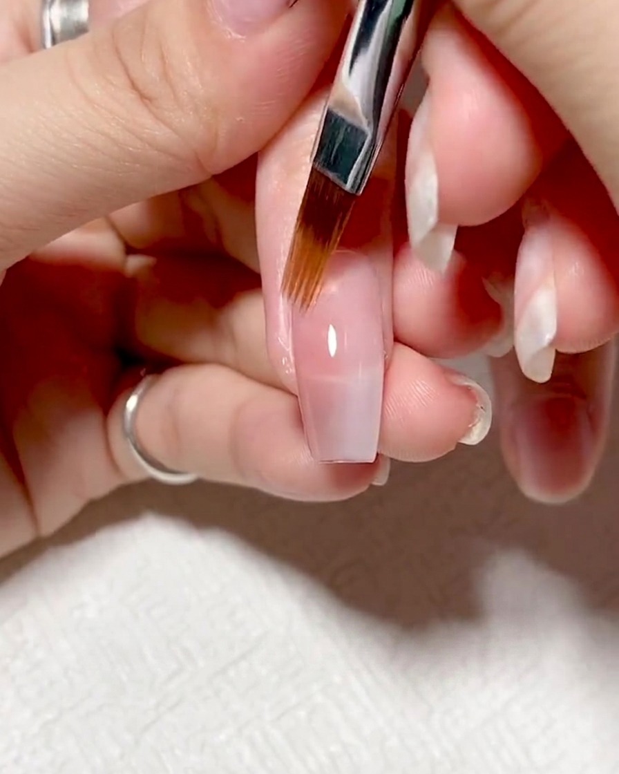 Uñas dentro de una lámpara UV/LED curándose bajo luz púrpura.