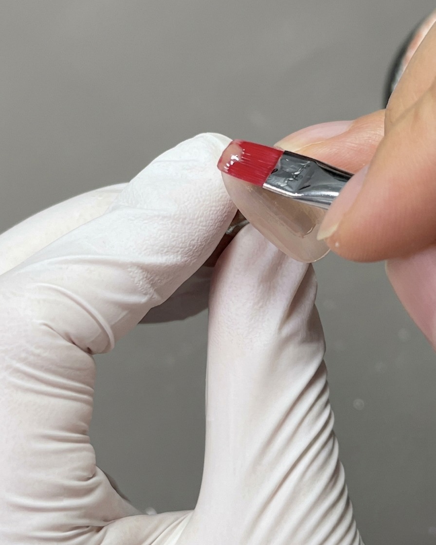 Un tip de uña colocado dentro de una lámpara UV para uñas durante el proceso de curado.