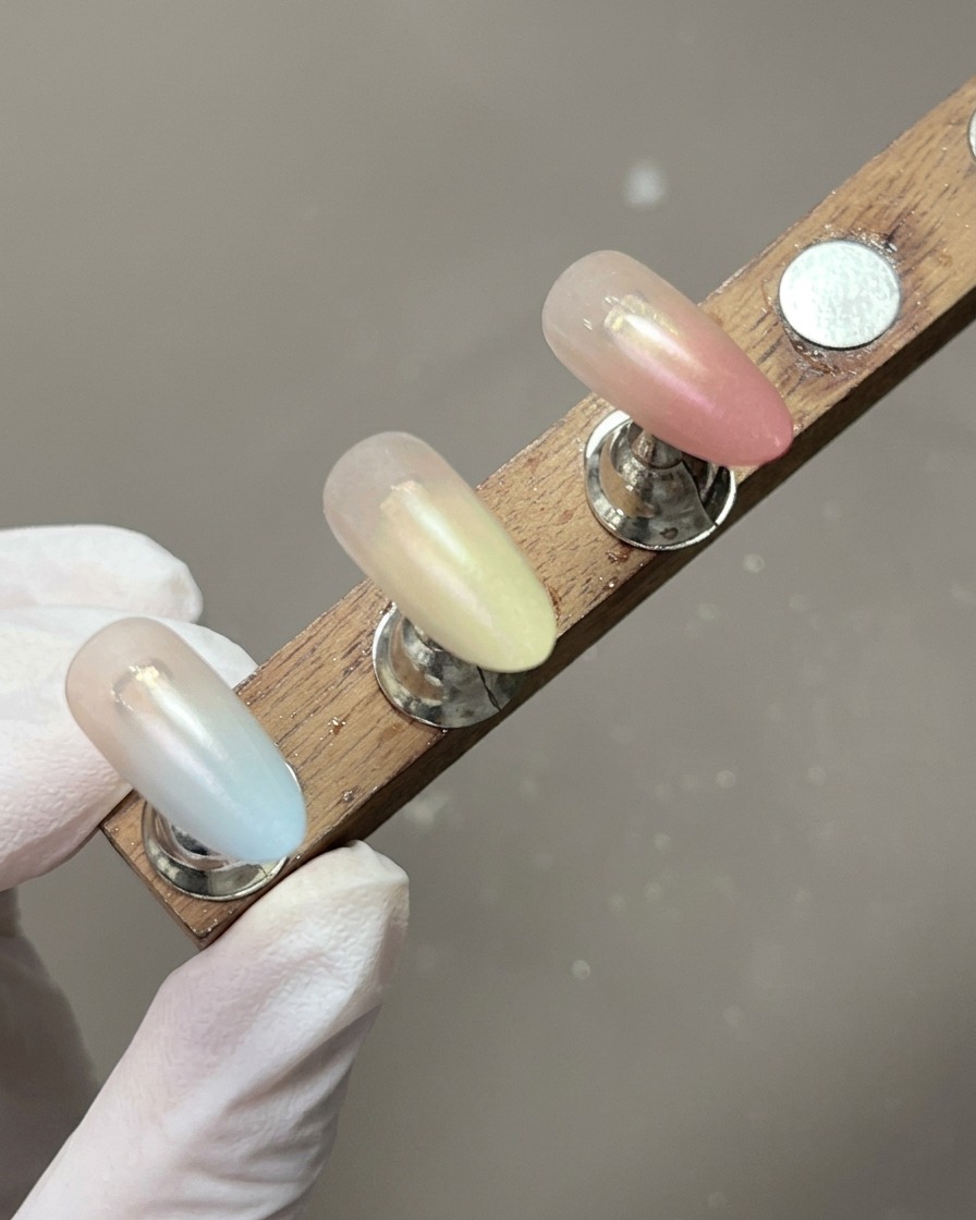 Un expositor mostrando tips de uñas con suaves degradados pastel terminados.