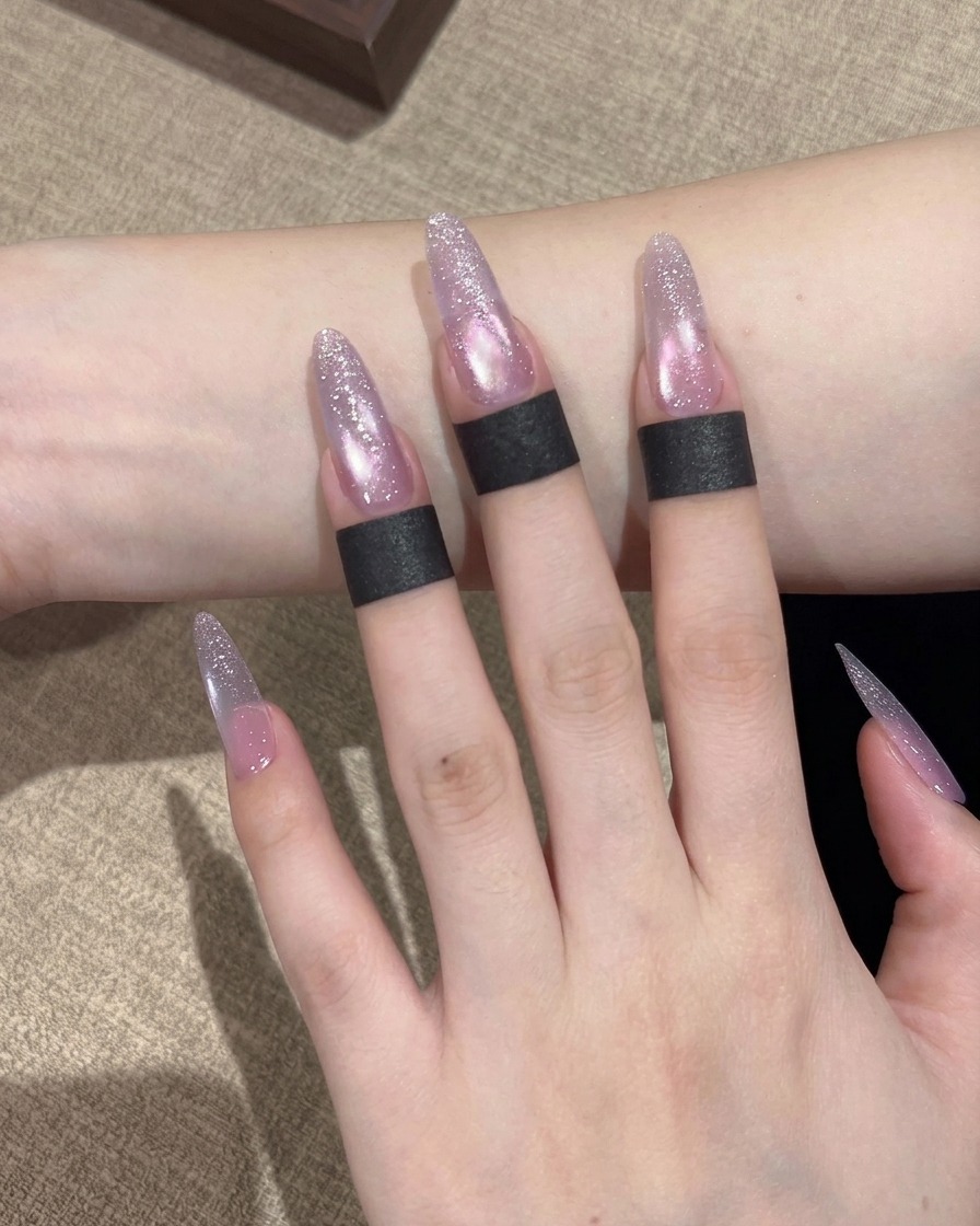 Un pincel aplicando esmalte gel cat eye en tono púrpura brillante sobre toda la superficie de la uña.