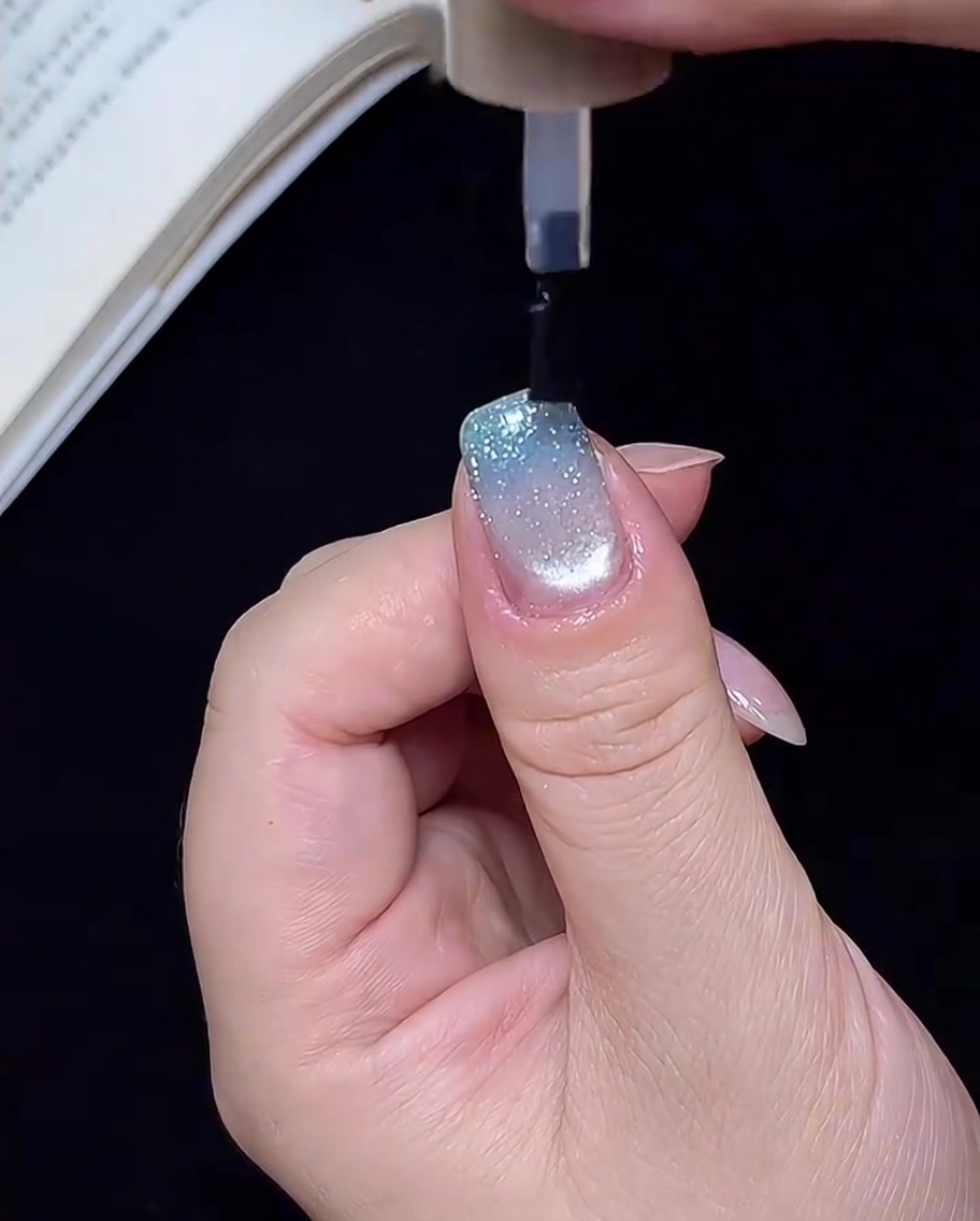 Una mano dentro de una lámpara UV/LED, con las uñas curándose bajo la luz para el paso final.