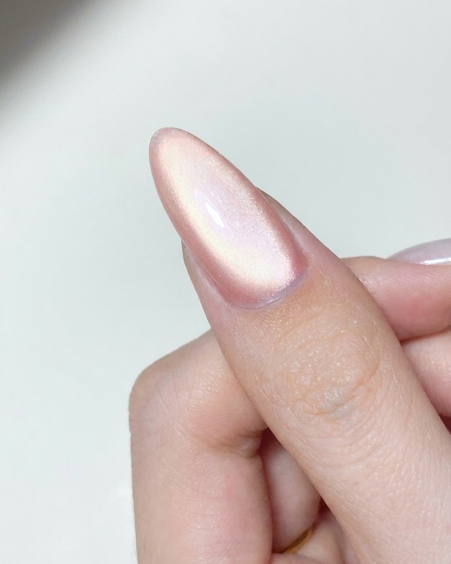 Una herramienta aplicadora puliendo polvo cromado aurora brillante sobre una superficie de uña de gel curada.