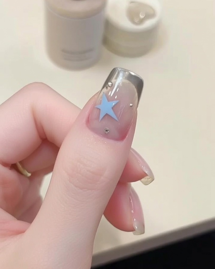Primer plano de un pincel de detalle aplicando gel azul para crear una estrella.