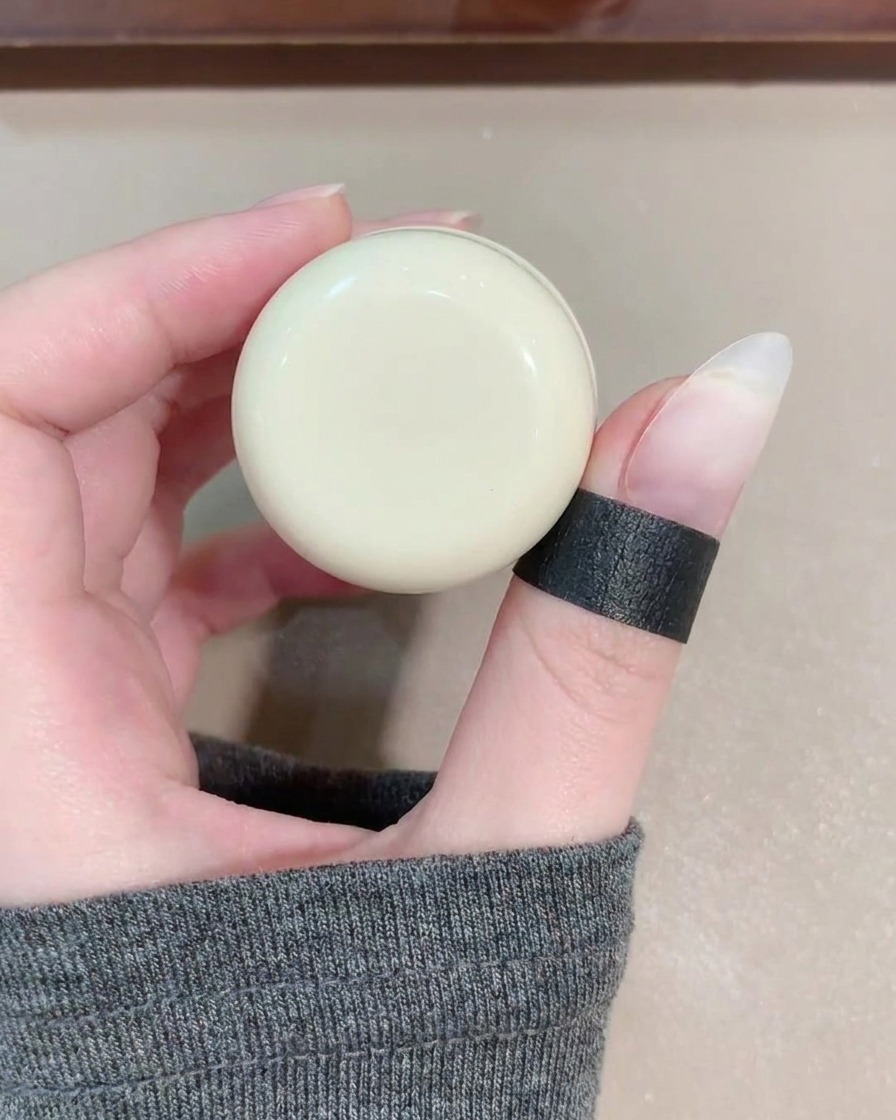Un pincel de gel aplicando una capa de esmalte cat eye azul traslúcido sobre la uña.