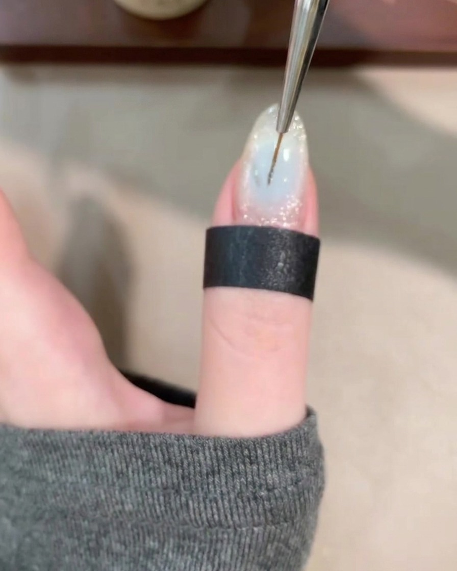 Un pincel liner fino dibujando líneas finas y onduladas sobre una base de gel transparente.