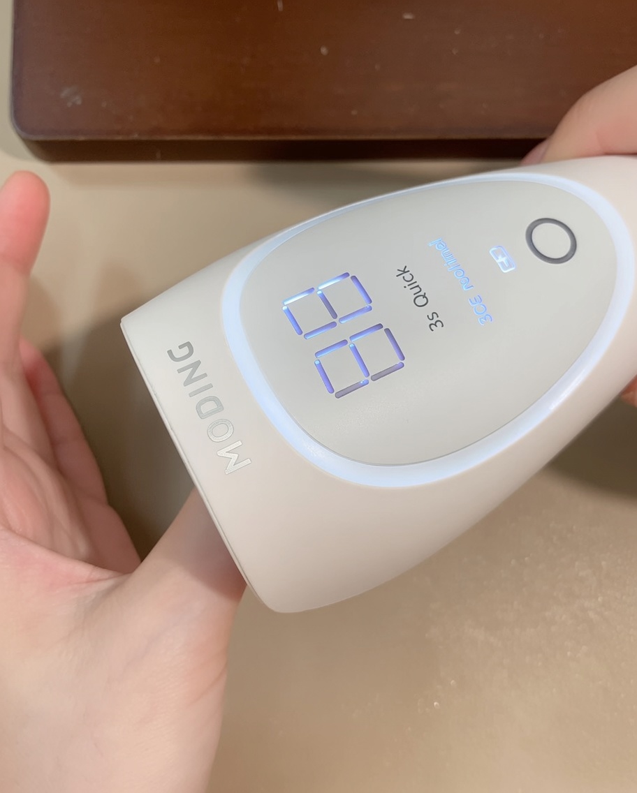 Mano bajo una lámpara LED portátil, con la pantalla digital indicando el tiempo de curado.