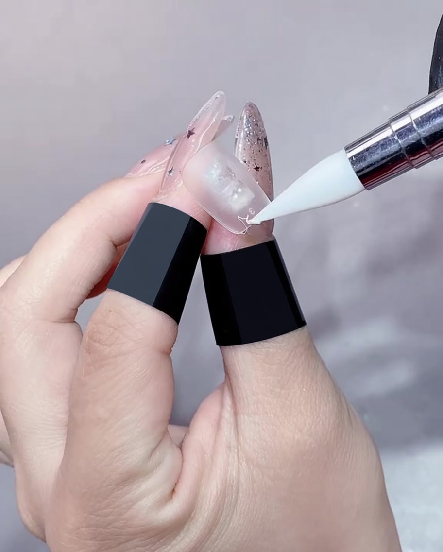 Primer plano de un pincel de gel aplicando gel transparente en el borde de una extensión de uña.