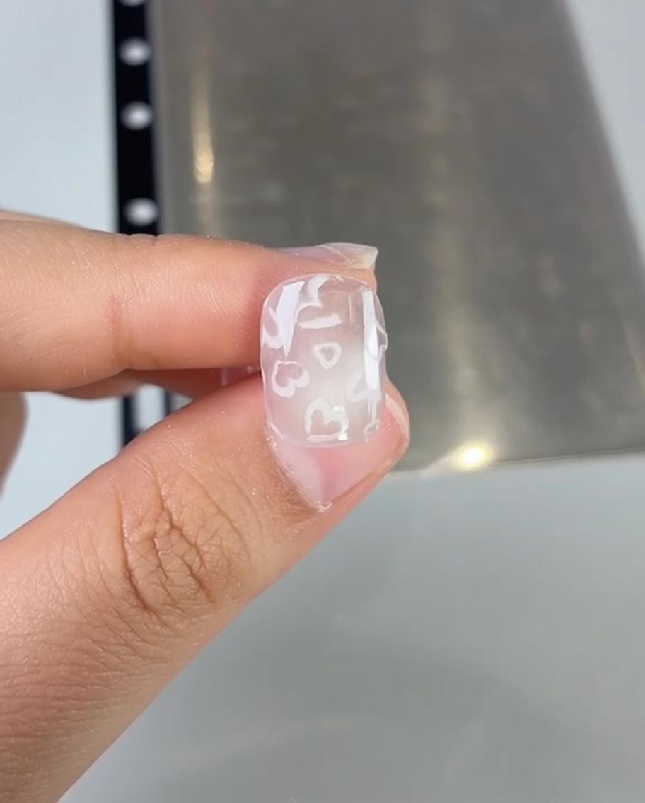 Primer plano de un pincel aplicando esmalte de gel rosa sobre la uña.