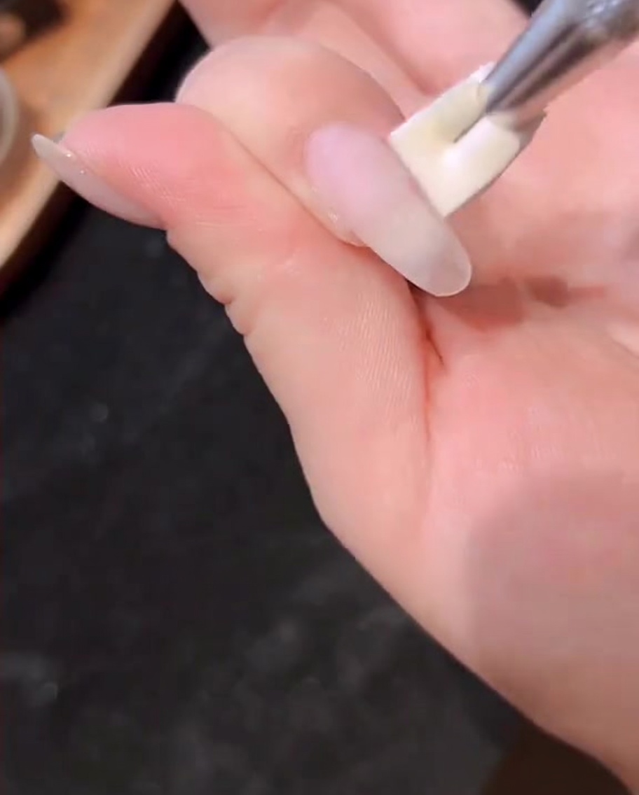 Una mano dentro de una lámpara UV/LED profesional encendida.