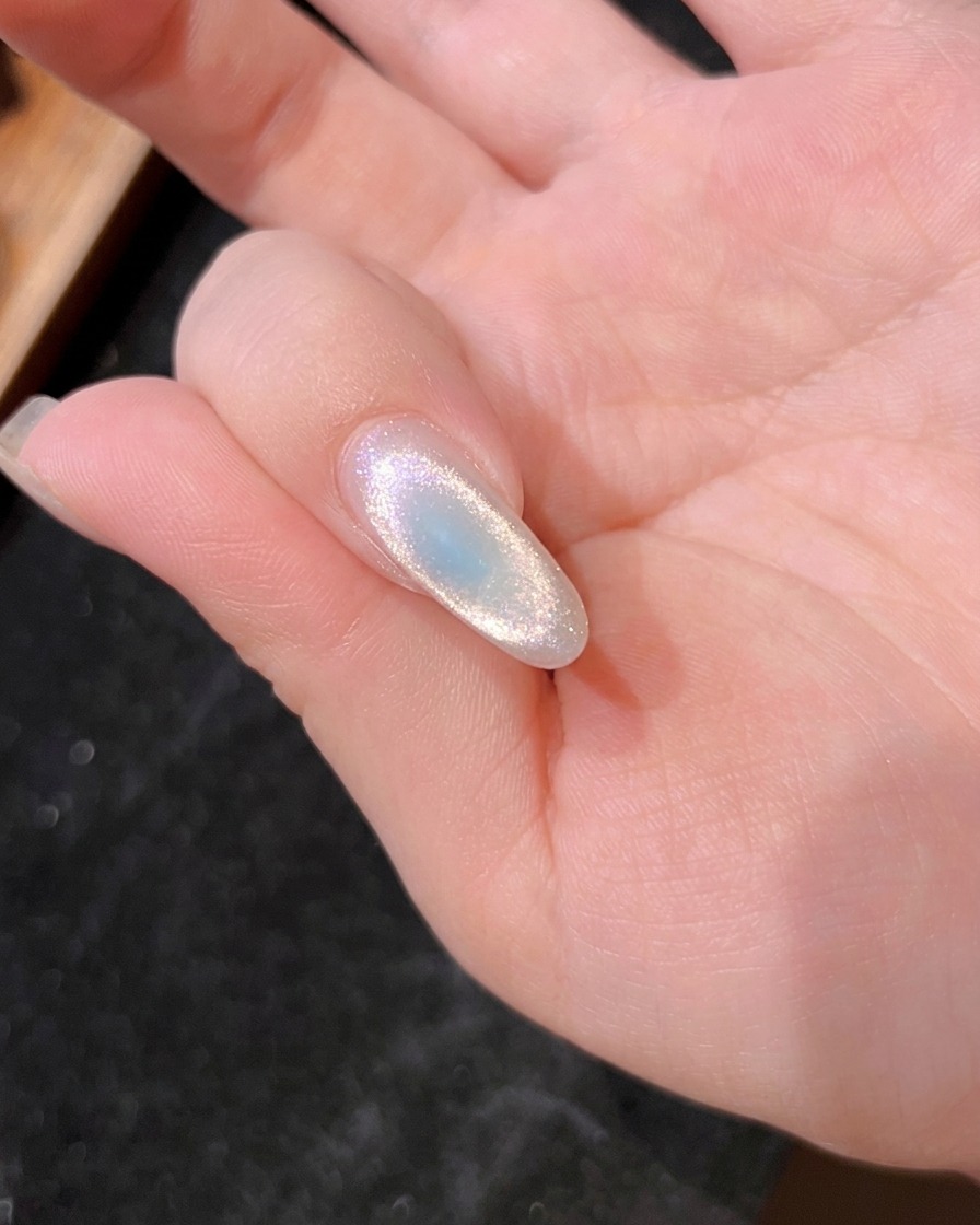 Primer plano de una uña bajo la lámpara, mostrando el curado del gel azul.